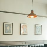 Copper pendant lamp hanging over a dark leather bench