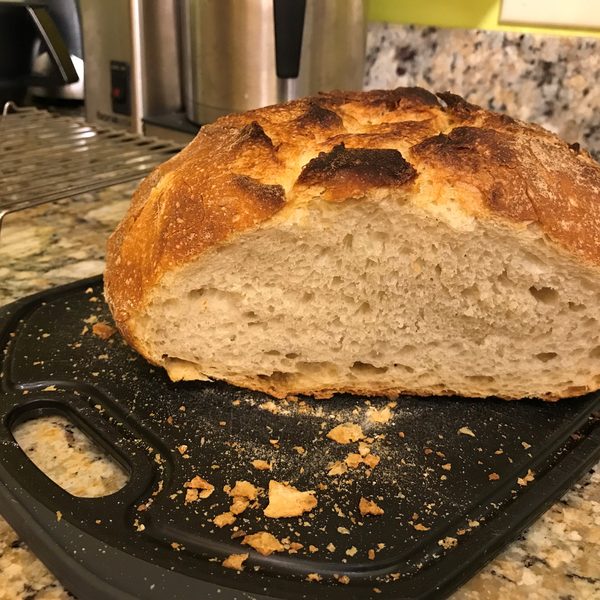 A crusty sourdough loaf cut open on a black board