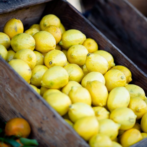 A wooden crate full of bright yellow lemons