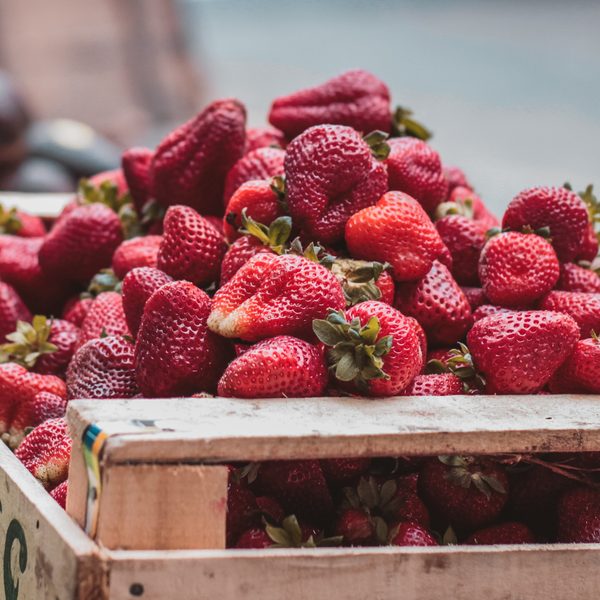 Ripe strawberries piled in a wooden market crate