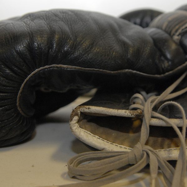 A pair of worn black leather boxing gloves