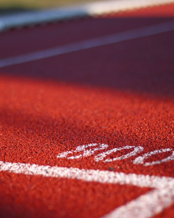 Close up of a red running track with white lane lines