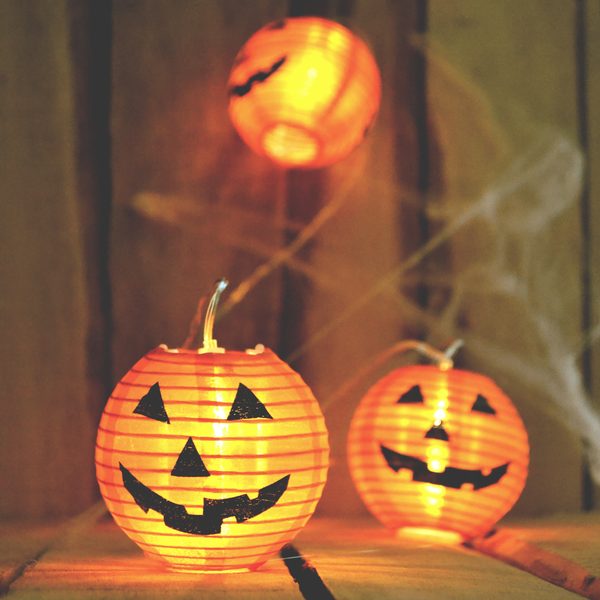 Two glowing paper lanterns with pumpkin faces in a dark doorway
