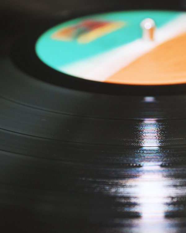 A vinyl record spinning on a turntable in low light