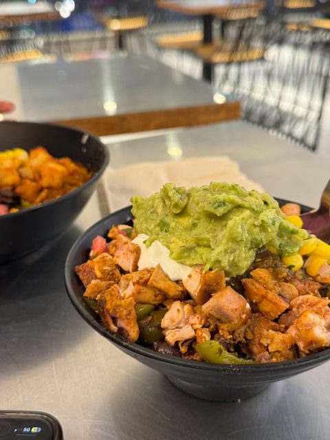 Rice bowl topped with avocado, roasted vegetables and tofu