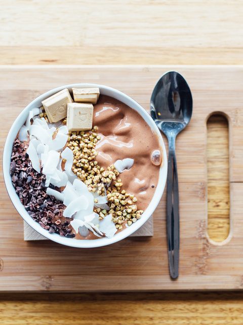 A cacao oat bowl with coconut and seeds on a wooden board