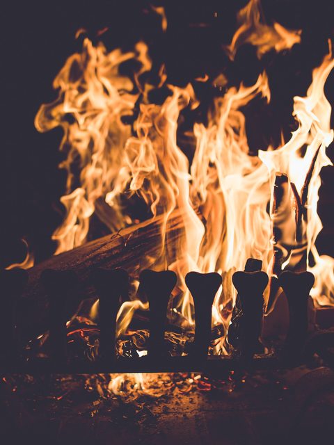 Bright flames rising from logs in a dark fireplace
