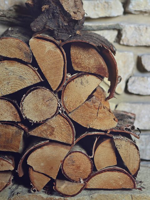 Split logs stacked neatly against a stone wall