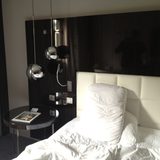 A made white bed with pillows beside a pendant lamp in a hotel room