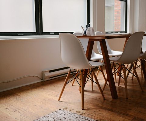 Wooden dining table with white chairs in a sunny room