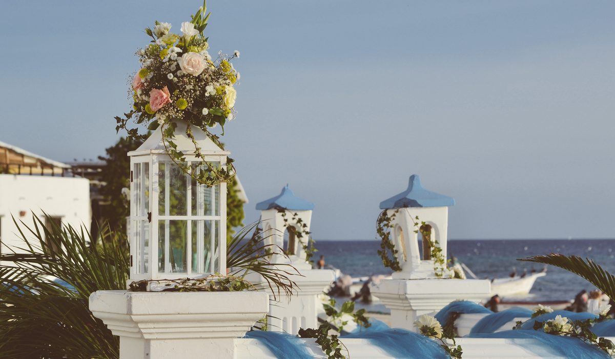 White seaside terrace with a flower covered lantern and blue water beyond