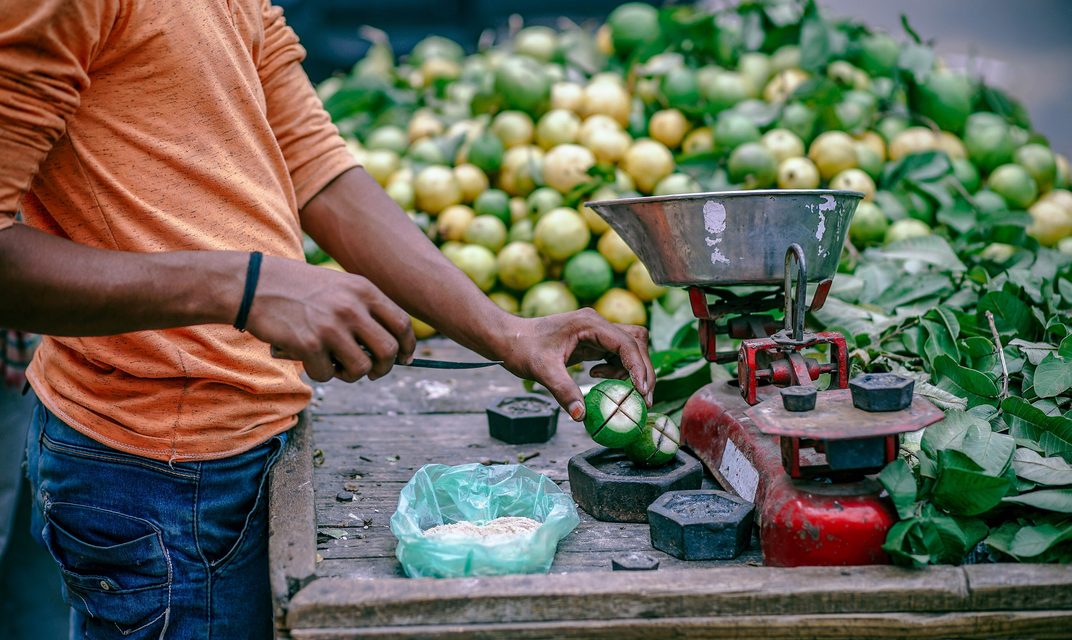 Fruit seller weighing limes on a scale at a street market stall