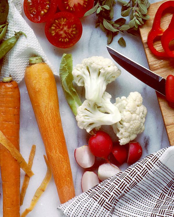 Carrots, cauliflower, radishes and sliced red pepper on a white board