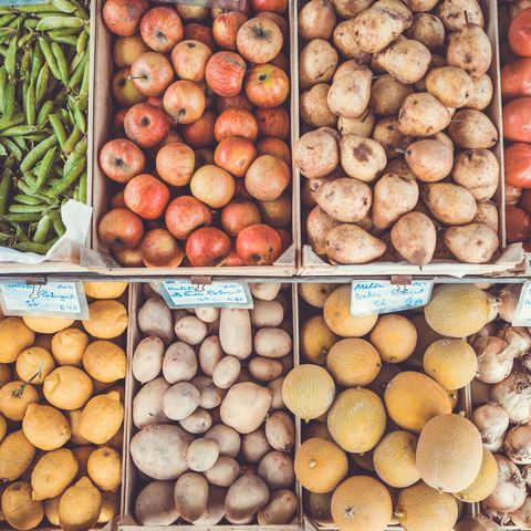 Crates of beans, apples, potatoes and tomatoes at a market
