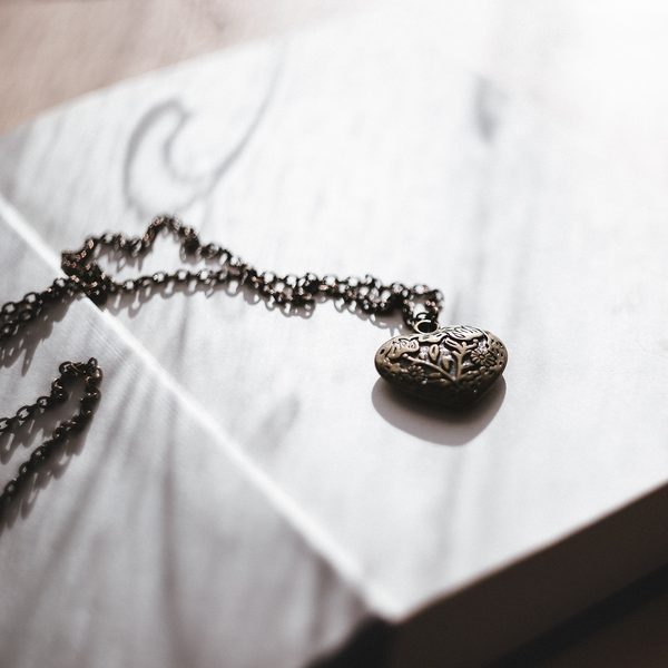 Silver heart locket on a chain resting on an open book