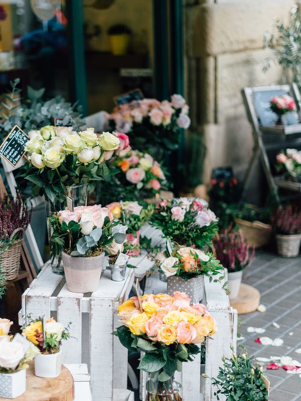 A flower shop front with buckets of roses and potted plants on the street