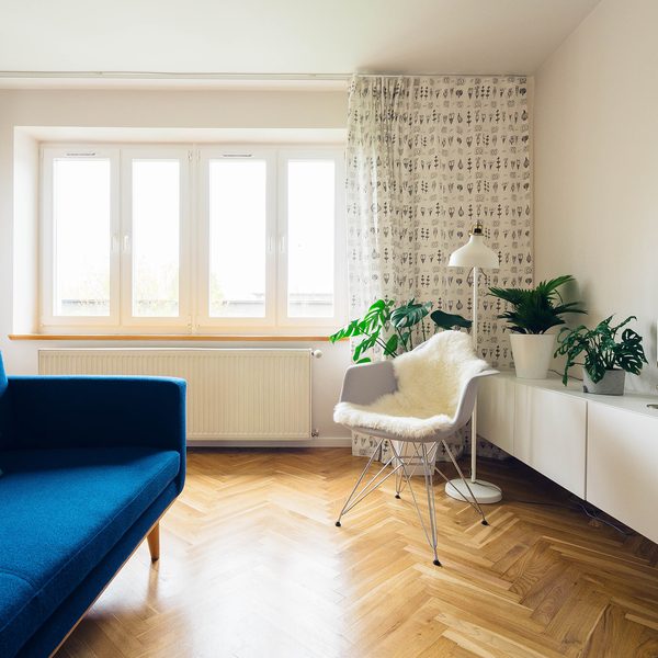 A sunny living room with a blue sofa and a herringbone wood floor