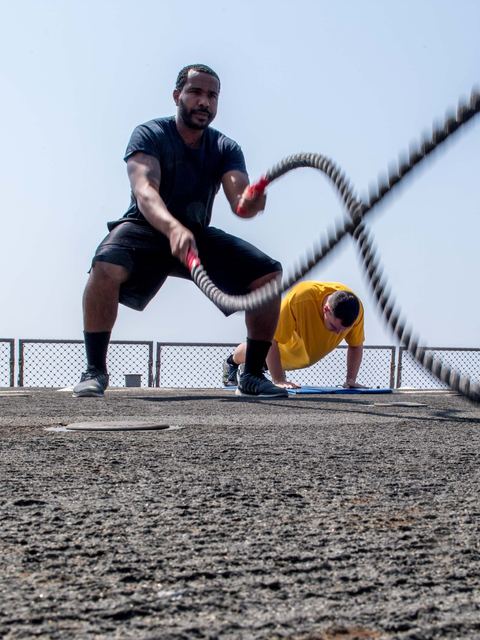 An athlete training with heavy battle ropes on an outdoor deck