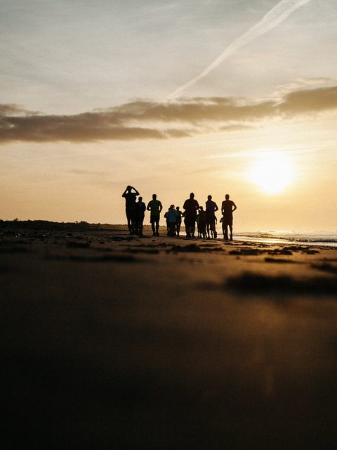 A group in silhouette on a beach watching the sun rise