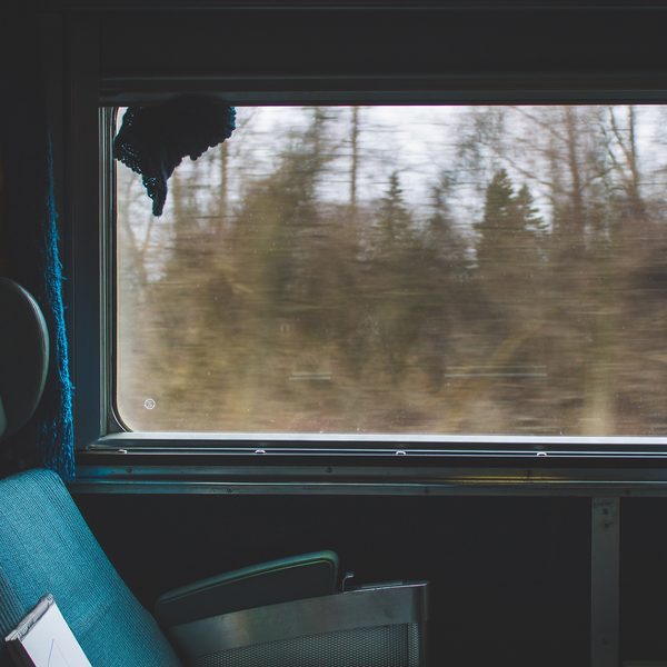 Blue train seats beside a window with blurred winter trees outside