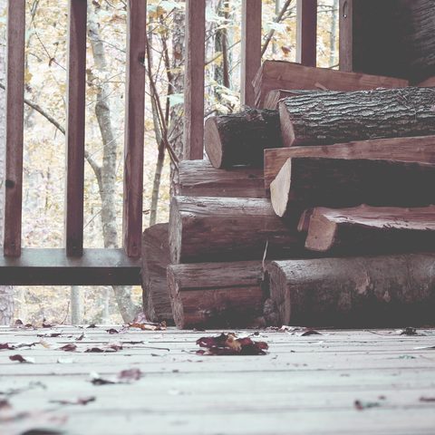 Stacked firewood on a wooden porch with a railing