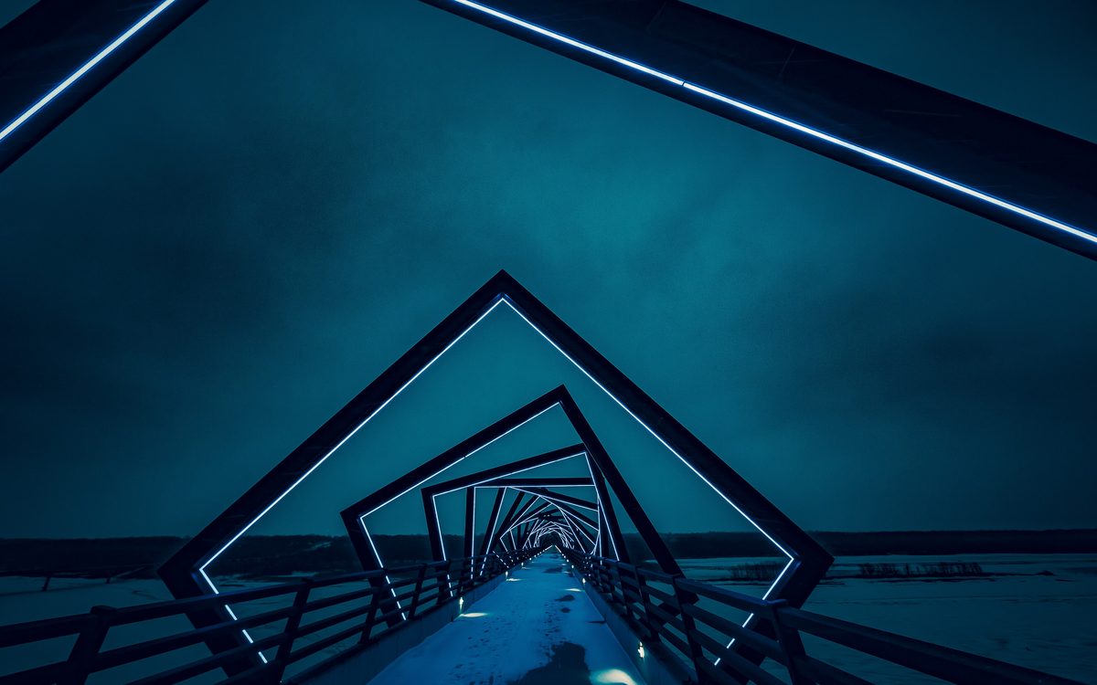 Square steel frames of a footbridge glowing blue at night