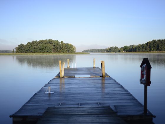 Short wooden pier on a still lake with a small island