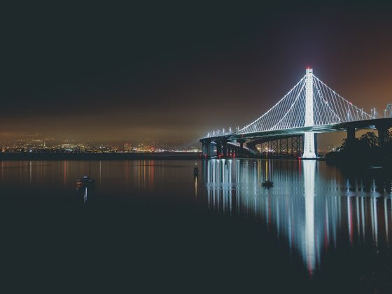 Suspension bridge lit white at night over dark water