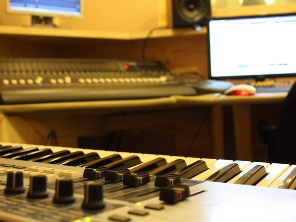A mixing desk, keyboard and monitor in a warmly lit studio