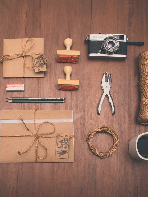 Kraft paper envelopes tied with twine beside rubber stamps and pencils