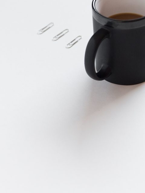 A black mug and a pen on a clean white desk