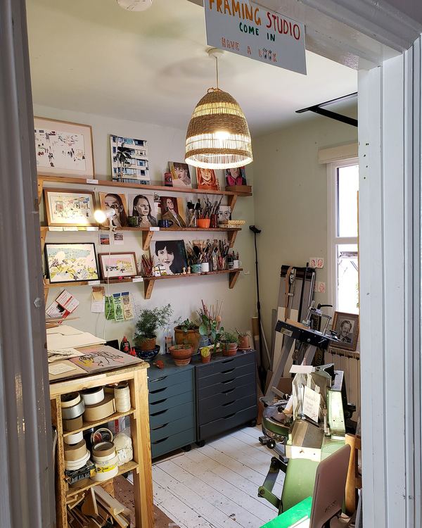 A small design studio with shelves of samples, a pendant lamp and a work table