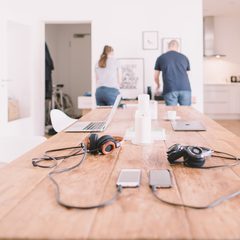 Two people talking at a long table with laptops