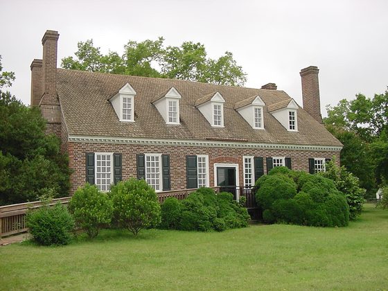 Brick colonial house with a green lawn and hedges