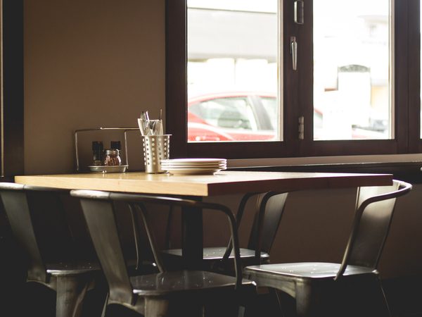 Wooden tables and metal chairs by a sunny window in a quiet dining room