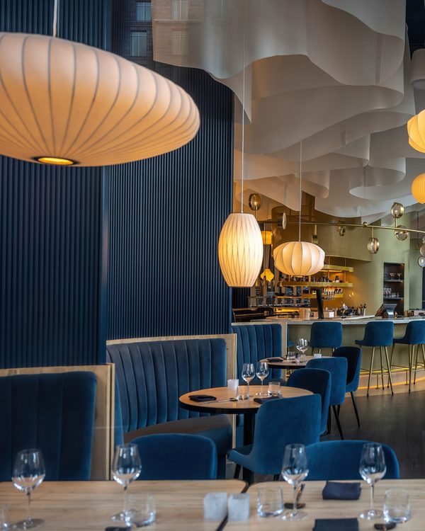 Dining room with blue velvet chairs, set tables and glowing paper lanterns