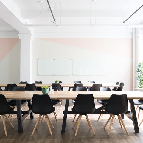 Bright meeting room with a long wooden table and black chairs