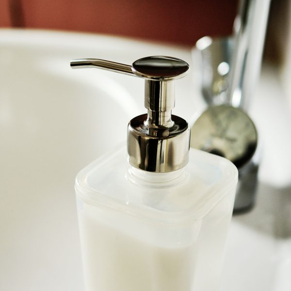 A frosted pump bottle of milky cleanser on a white sink