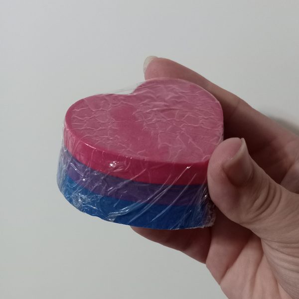 A pink and blue heart shaped soap bar held in one hand