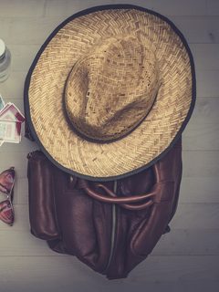 Straw sun hat resting on a brown leather bag