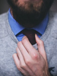 Grey knit sweater worn over a white shirt and tie