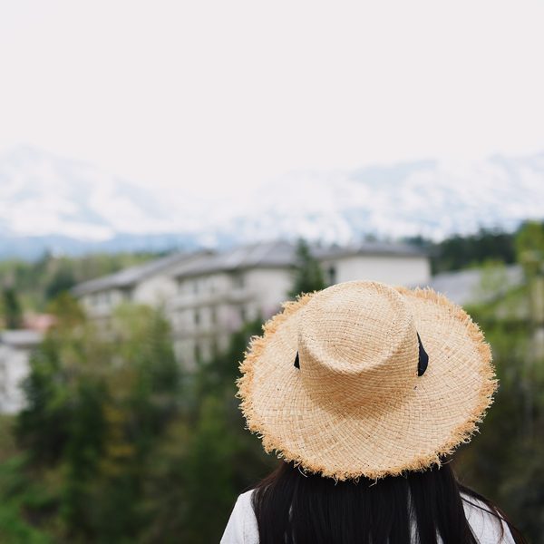 A woven straw sun hat with a black band resting in tall green grass