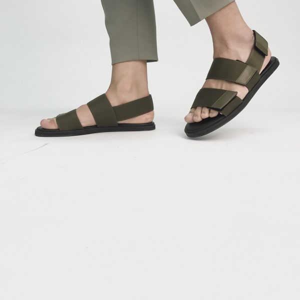 Olive green strap sandals worn on a plain white floor