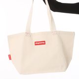 Natural canvas tote bag held up by one hand