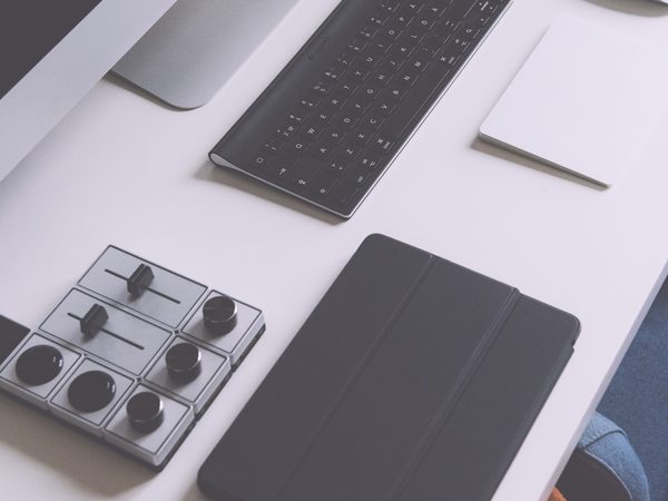 Tablet, phone and keyboard laid out on a grey desk