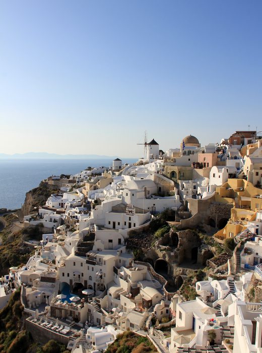 White houses and a windmill on a cliff above the sea