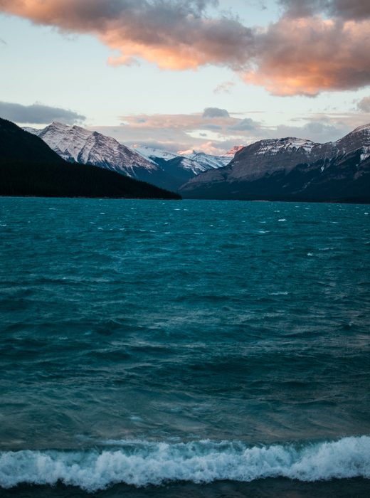 Deep blue mountain lake under pink evening clouds