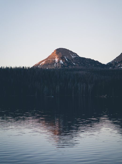 Still dark lake below a mountain at dusk