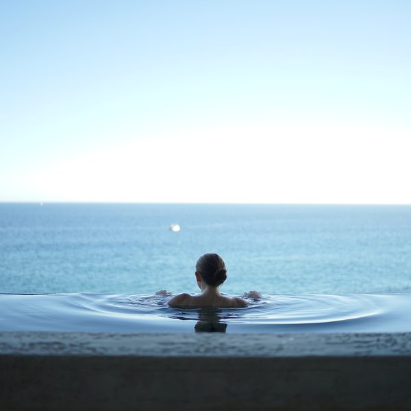 A guest seen from behind in an infinity pool looking out to sea