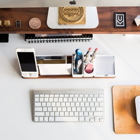 Top view of a tidy desk with a keyboard, phone stand and pen tray